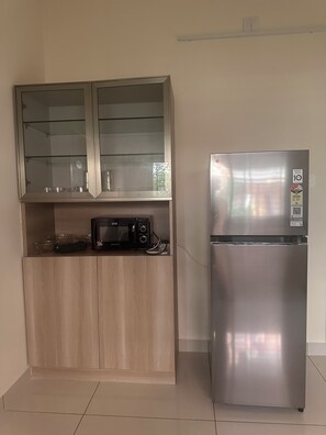 Eine Küche mit Mikrowelle, einem Edelstahlkühlschrank und einem Holzschrank mit Glasschiebefront.