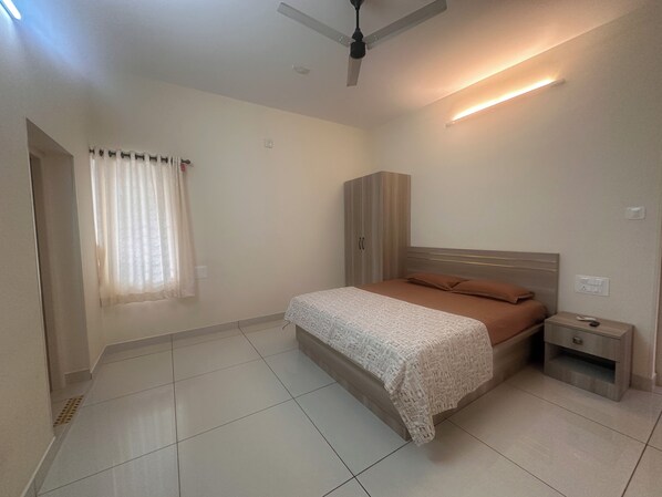 A bedroom with a bed, nightstand, wardrobe, and a ceiling fan.