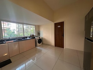 A modern kitchen with a built-in washer and dryer, a large window, and a door labeled 'UNIT 1'.