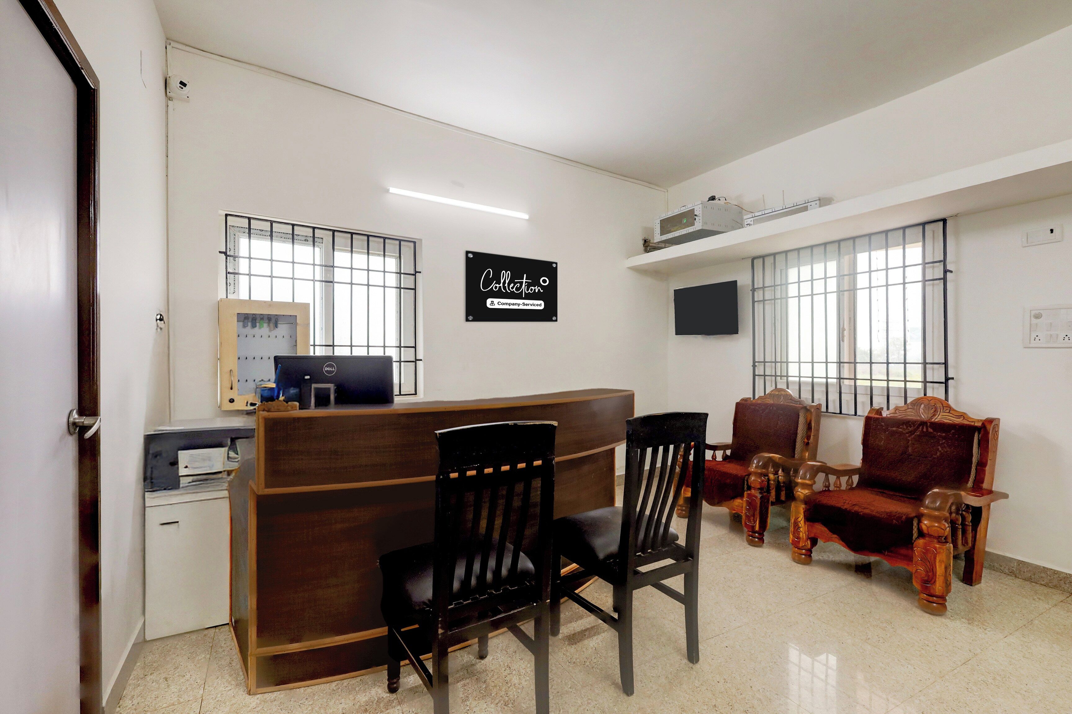 Un espace d’accueil comprenant un bureau, un ordinateur et deux chaises en bois.