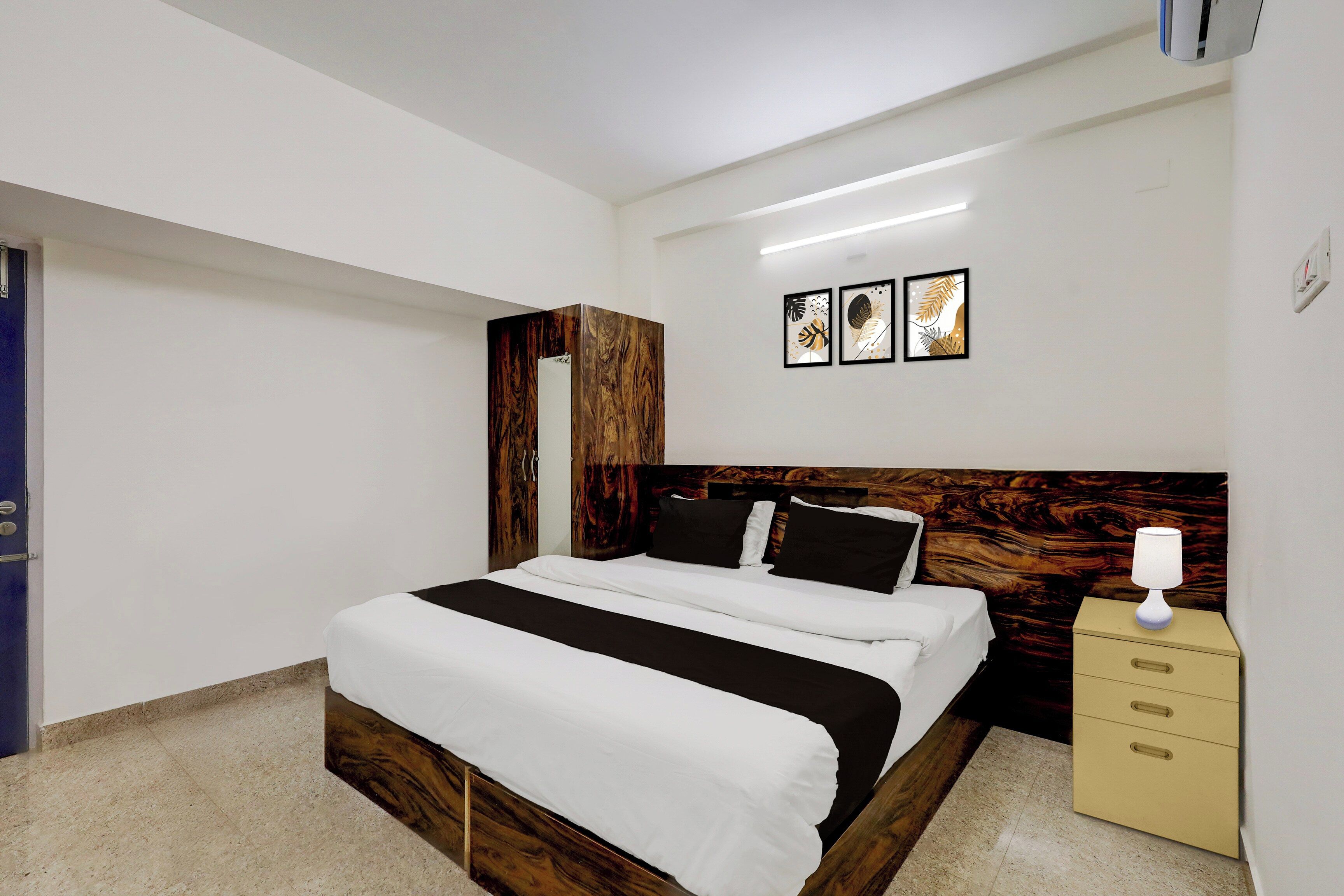 A bedroom with a bed, a nightstand, a lamp, and wall art.