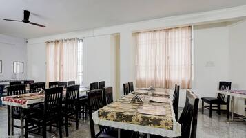 Een vergaderzaal met een lange tafel, meerdere stoelen en een plafondventilator.