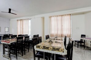 Une salle de conférence avec une longue table, de nombreuses chaises et un ventilateur de plafond.