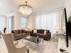 A modern living room with a chandelier, two sofas, a coffee table, and a TV. - Golf Themed 4BR · Private Pool · ChampionsGate (Davenport)