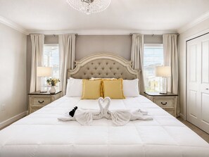 Ein Hotelzimmer mit einem großen Bett, zwei Nachttischen mit Lampen, einer Kronleuchter und Blick ins Freie.