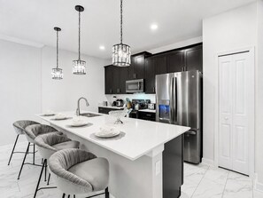 A modern kitchen with a central island, stainless steel appliances, and pendant lighting. - Golf Themed 4BR · Private Pool · ChampionsGate (Davenport)