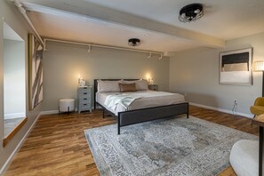A bedroom with a bed, bedside tables, a rug, and a ceiling light fixture. - Wall Street Suites 1 | King Suite near SIU with Kitchen (Carbondale)
