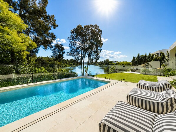 Piscina com vista clara da paisagem ao redor, incluindo árvores e um corpo d'água distante.