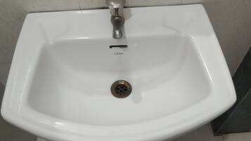 A white ceramic sink with a single faucet and a drain.