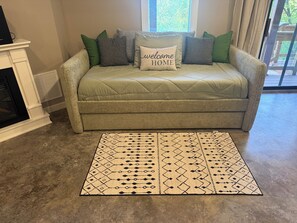 A beige sofa with a quilted cover, multiple cushions, and a 'welcome home' pillow. A patterned rug is placed in front of the sofa. - Tranquil 1-bedroom guest suite In Bella Vista Hills (Bella Vista)