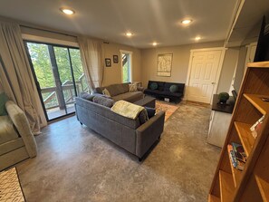A spacious living room with a grey sofa, a black sofa, and a wooden bookshelf. - Tranquil 1-bedroom guest suite In Bella Vista Hills (Bella Vista)