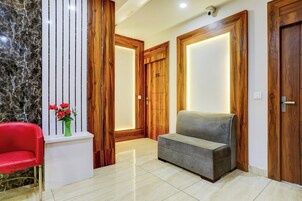 A modern interior with a marble wall, wooden doors, a red chair, and a grey sofa.