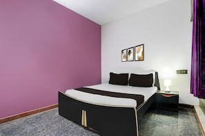 Una habitación de hotel con una cama, una mesita de noche, una lámpara y un cuadro colgado en la pared.