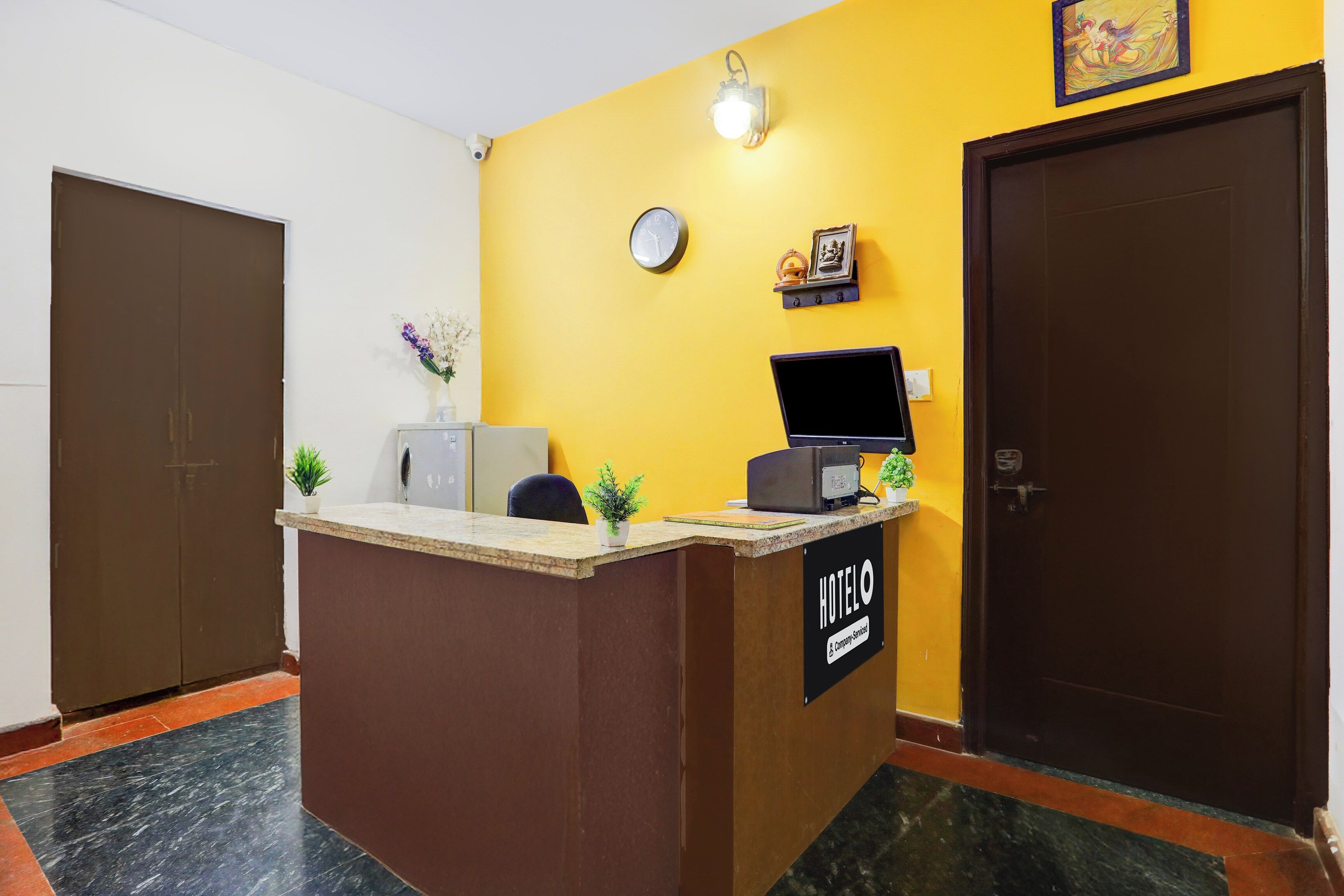 A hotel reception desk with a clock, a small statue, and a sign that reads 'HOTEL & Company Services'.