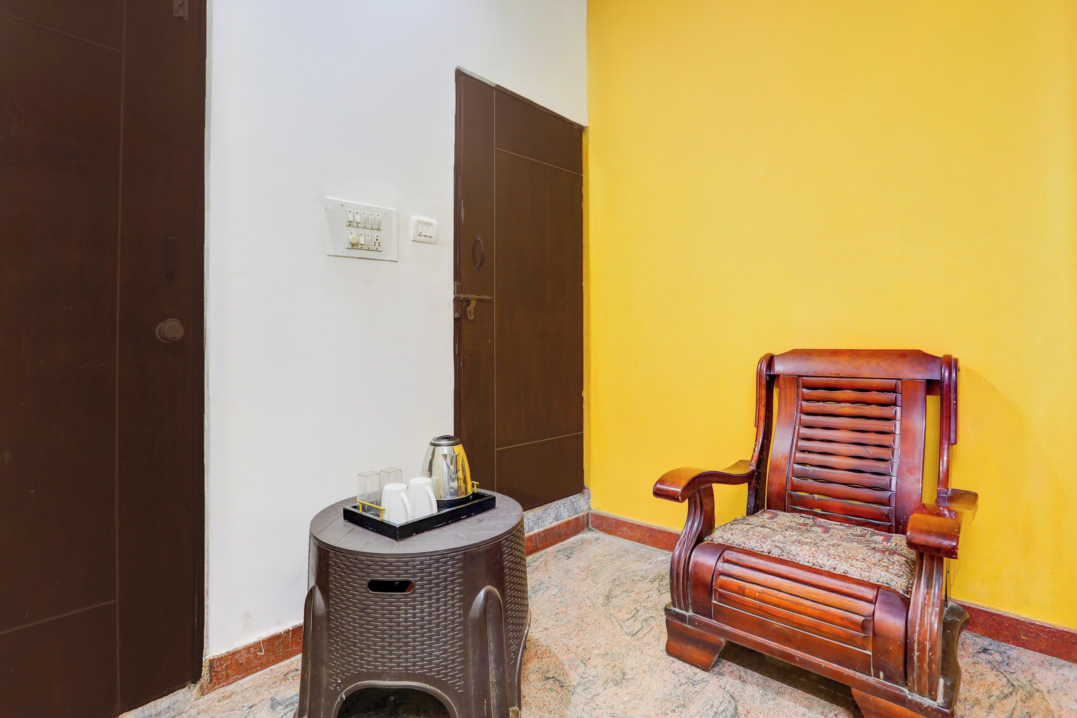 A room with a wooden chair, a small stool, and a wall socket.