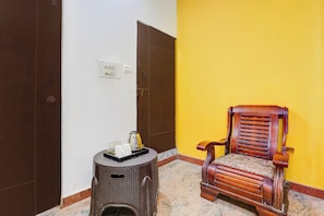 A room with a wooden chair, a small stool, and a wall socket. - Hotel O Kogilu Bus Terminal (Bangalore)