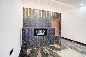 Un mostrador de recepción de hotel con diseño moderno, un cartel que indica servicio de empresa y un suelo de mármol pulido.