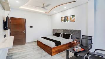Un dormitorio moderno con cama, escritorio, silla, televisor y obras de arte en la pared.