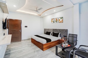 A modern bedroom with a bed, a desk, a chair, a TV, and artwork on the wall.