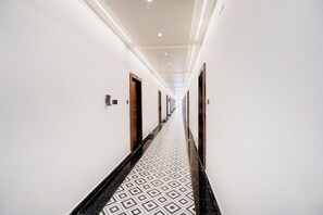 Pasillo de hotel con piso estampado, puertas y techo con iluminación empotrada.