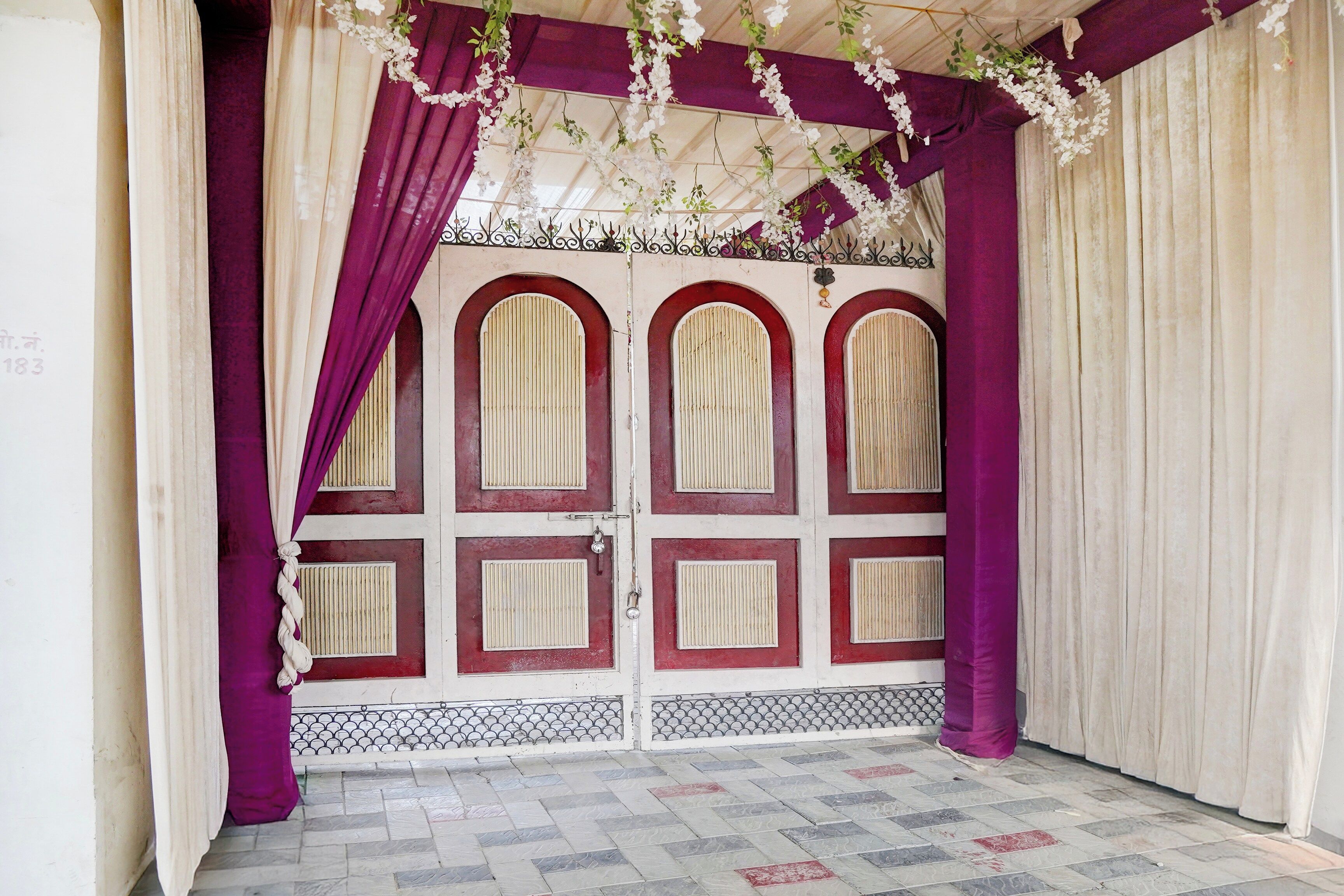 A room with a patterned tiled floor, a white door with red accents, and purple curtains.