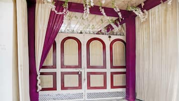 A room with a patterned tiled floor, a white door with red accents, and purple curtains.