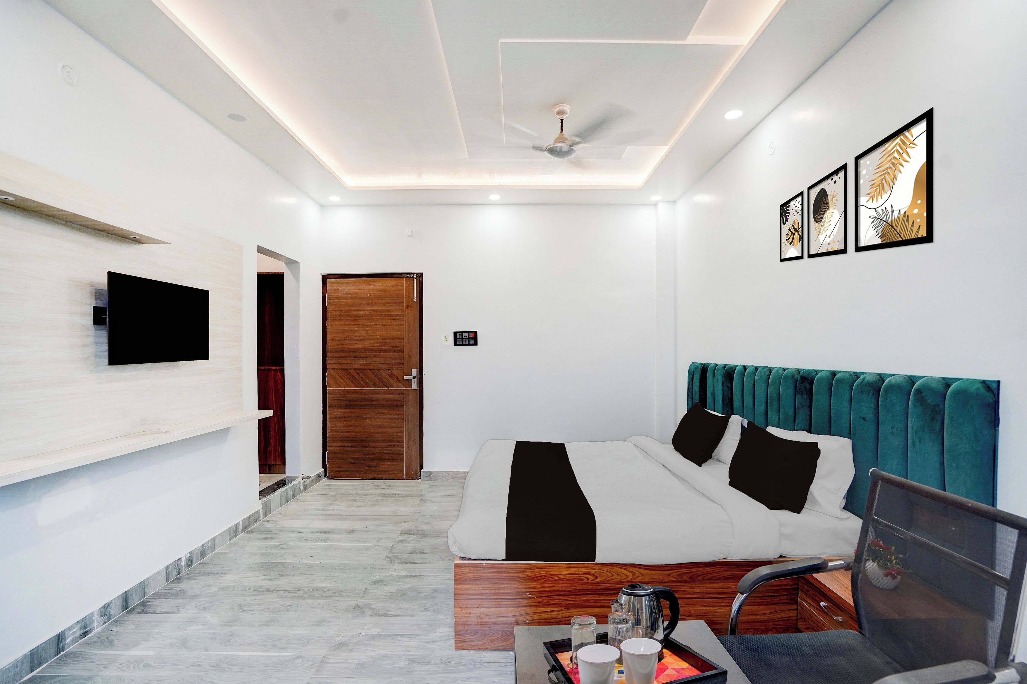 Une chambre moderne comprenant un lit, un bureau, une chaise, un téléviseur et un ventilateur de plafond.