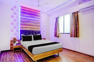 Quarto com cama, mesa de cabeceira e janela com cortinas.