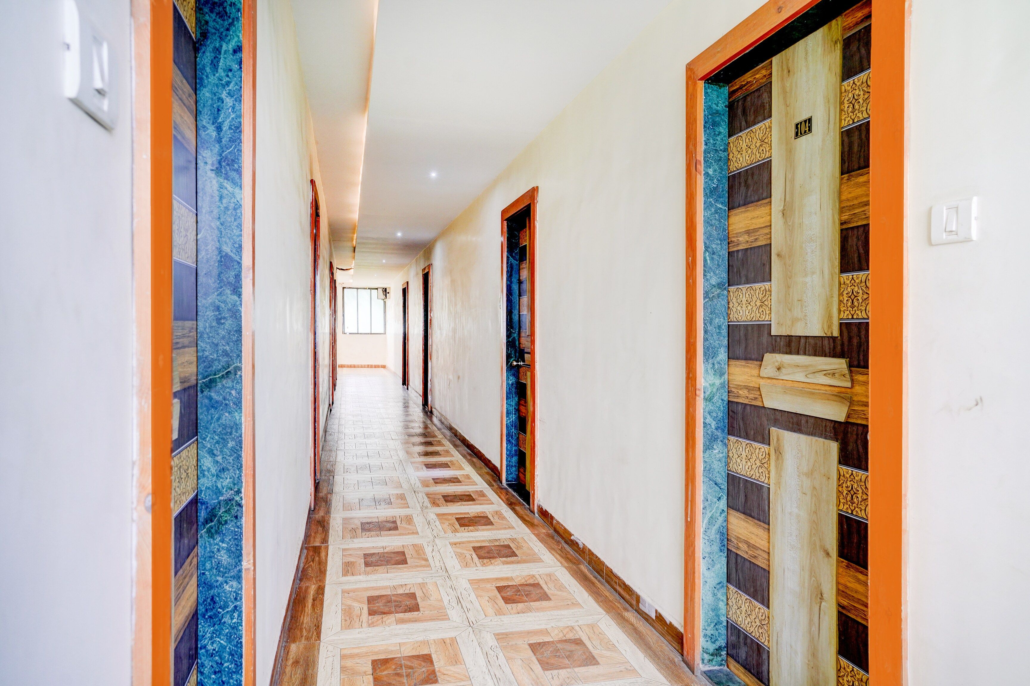 A hallway with patterned flooring, wooden doors with decorative panels, and a light-colored wall.
