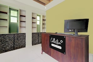 Una zona de recepción con un mostrador de madera, un televisor y un cartel que dice 'Collection Company - Serviced'.