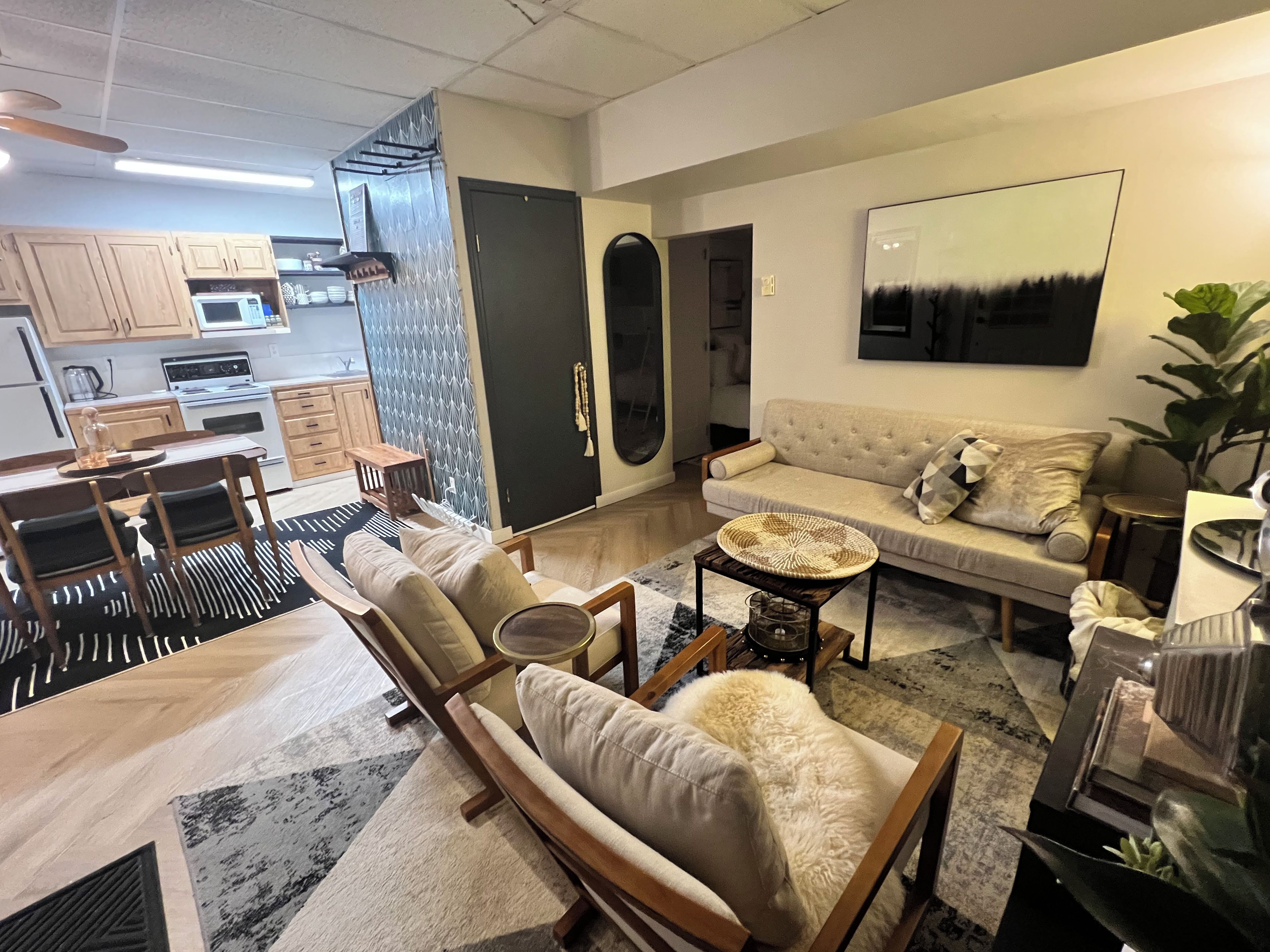 A modern living room with a sofa, armchairs, a coffee table, and a dining area with a table and chairs.