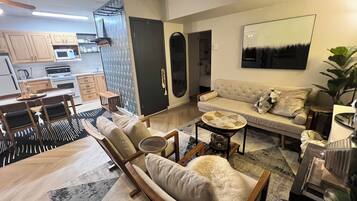 A modern living room with a sofa, armchairs, a coffee table, and a dining area with a table and chairs.