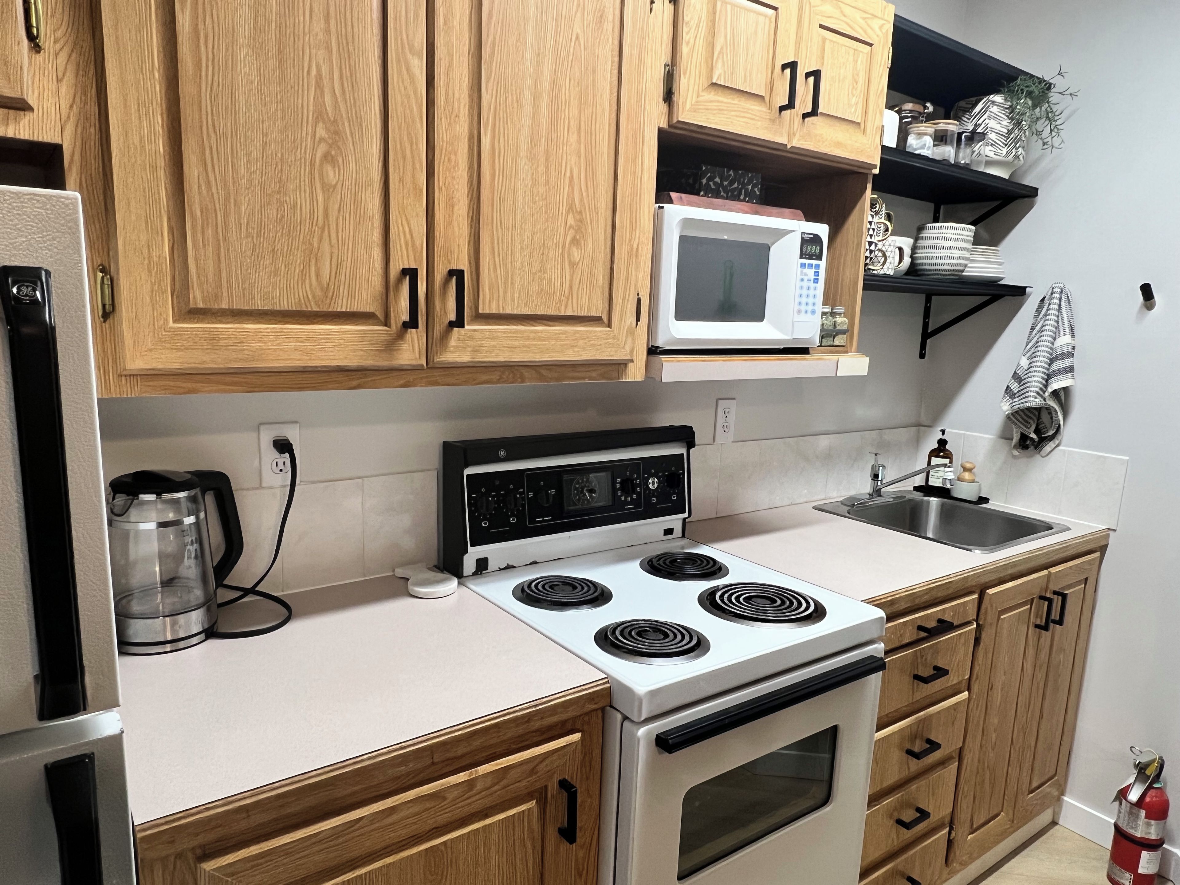 A kitchen with wooden cabinets, a microwave, a stove, a coffee maker, and a sink.
