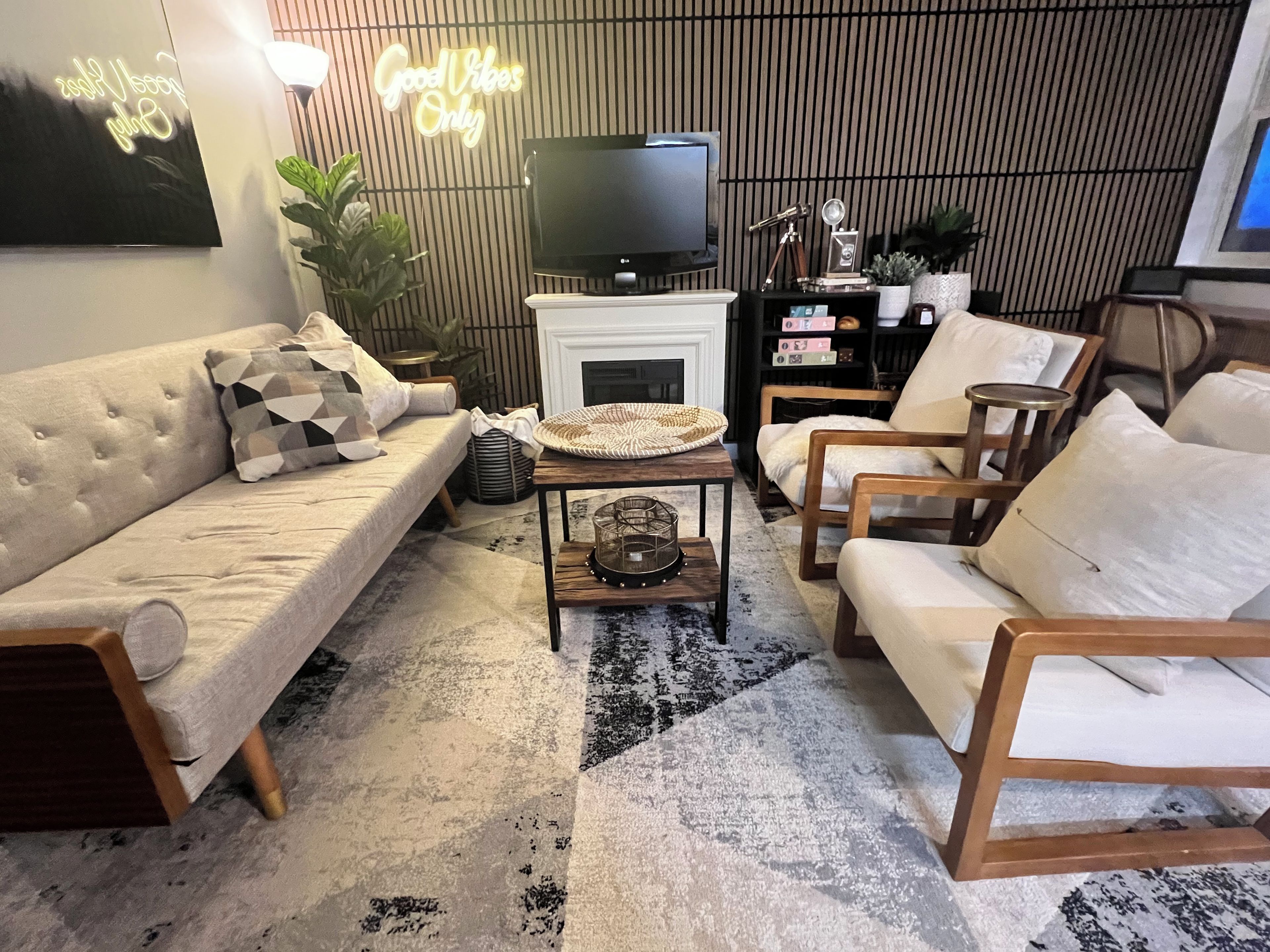 A modern living room with a sofa, armchairs, a coffee table, a television, and a fireplace.