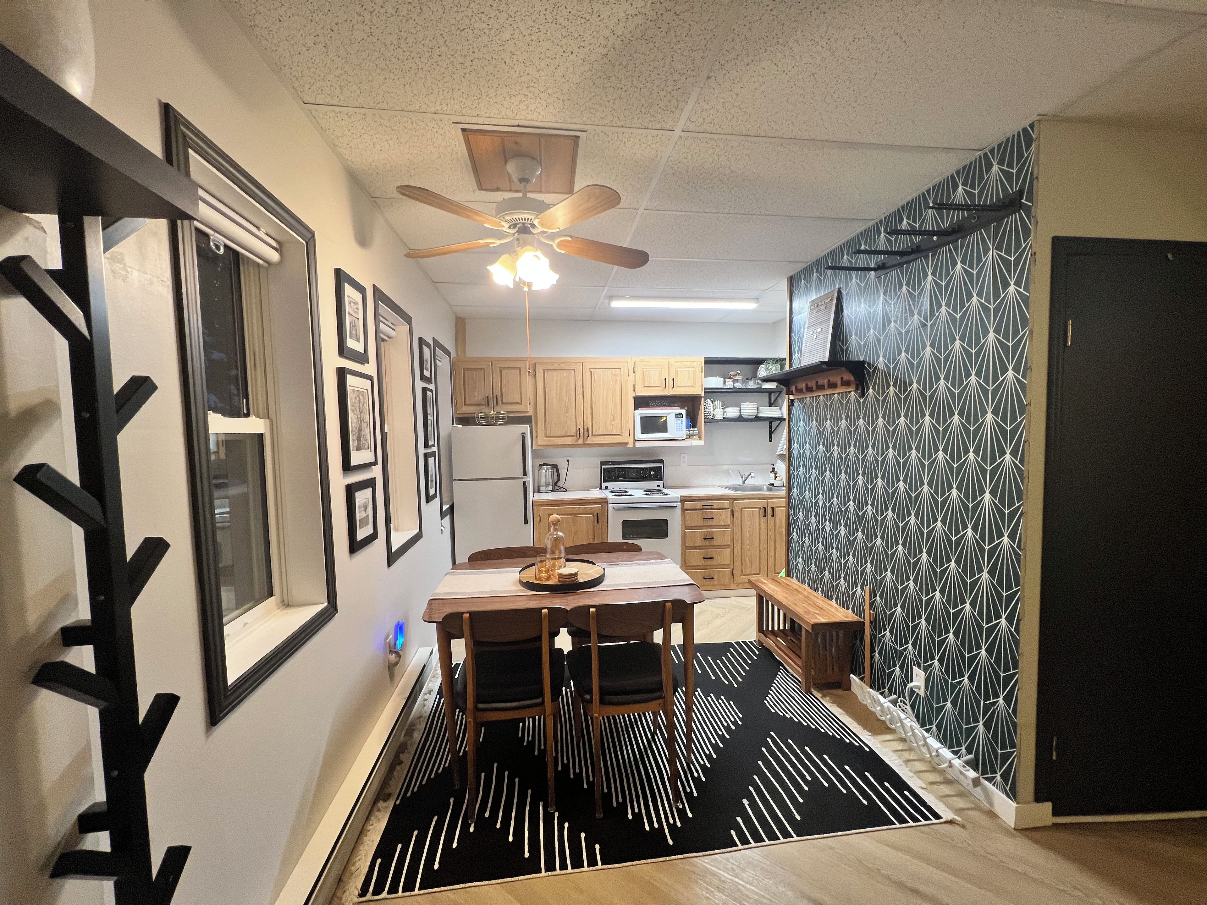 A modern kitchen with wooden cabinets, a microwave, and a ceiling fan.