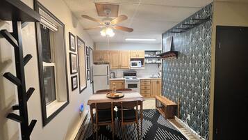 A modern kitchen with wooden cabinets, a microwave, and a ceiling fan.