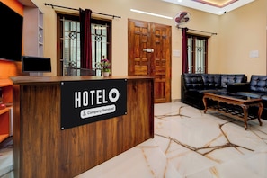 Una recepción de hotel con un letrero que indica servicio de empresa. Hay un sofá de cuero negro y una mesa de centro de madera en el vestíbulo.