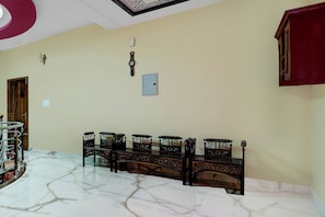 A room with a marble floor, a bench, a wall clock, and a door.