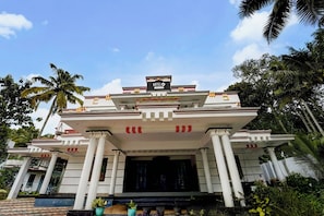 A hotel with a modern architectural design, featuring a prominent entrance with columns and a signboard. - Hotel O NIMS Hospital (Neyyattinkara)