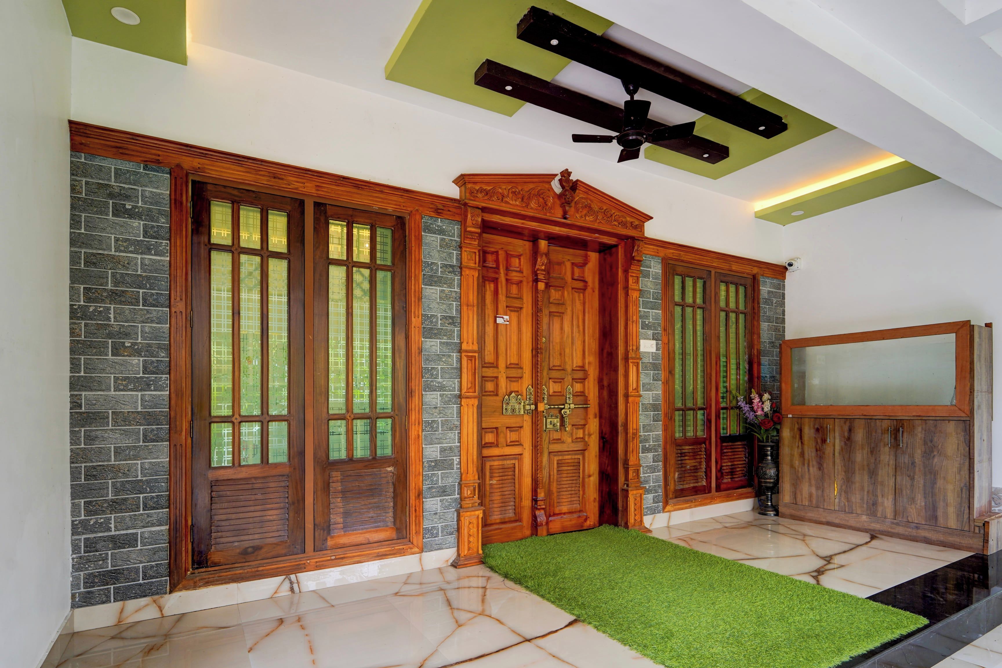 Una habitación con puerta de madera, ventilador de techo y un tapete de césped artificial verde.