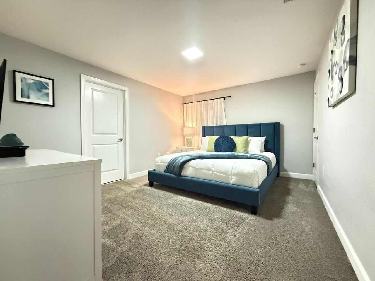 Un dormitorio con una cama, un tocador y una puerta.