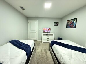 A bedroom with two beds, a white dresser, a television, and a door. - LUXURY 5BR PRIVATE POOL 8 MIN TO DISNEY SLEEPS 13 (Kissimmee)