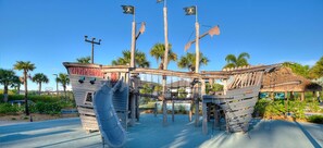 A pirate-themed play structure with slides and climbing areas, surrounded by palm trees and a clear sky. - LUXURY 5BR PRIVATE POOL 8 MIN TO DISNEY SLEEPS 13 (Kissimmee)