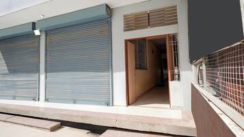 A building with closed roller shutters, a visible entrance, and a gated area.