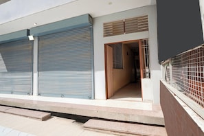 A building with closed roller shutters, a visible entrance, and a gated area. - Hotel O Kukas Bus Terminal (Amer)