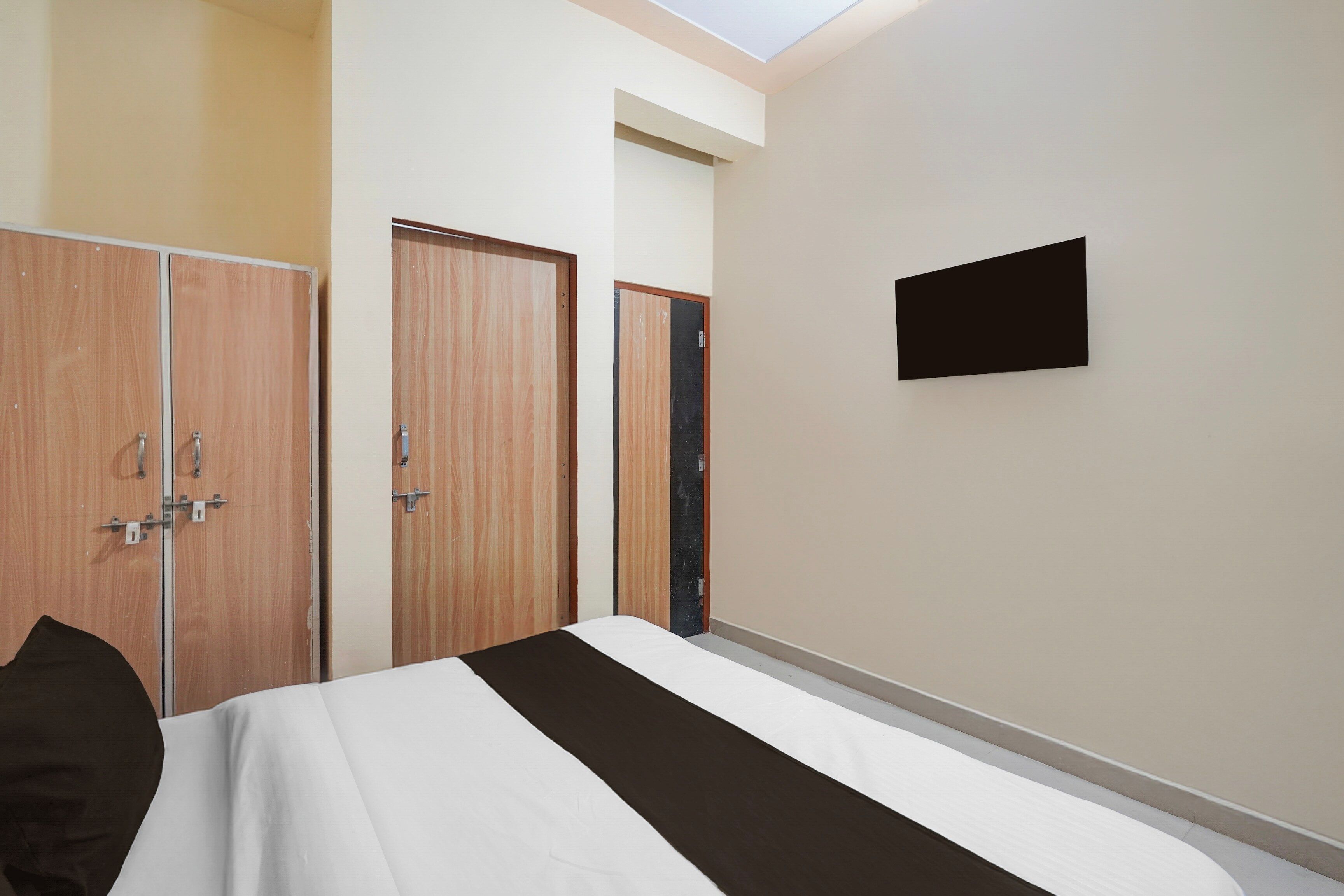 A bedroom with a bed, two wardrobes, a flat-screen TV, and a skylight.