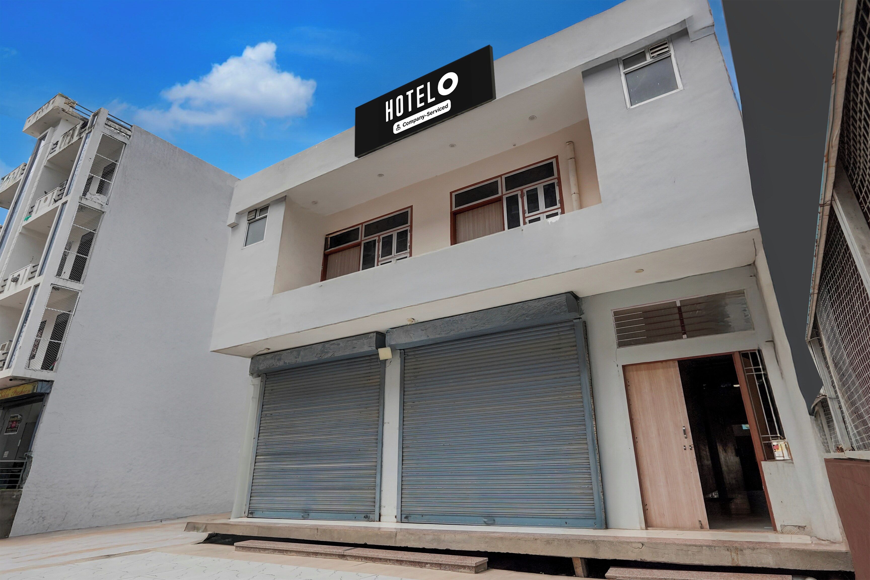 Un hotel con letrero, persianas cerradas y cielo despejado.