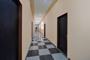 A corridor with checkered flooring leading to doors on both sides. - Hotel O Kukas Bus Terminal (Amer)