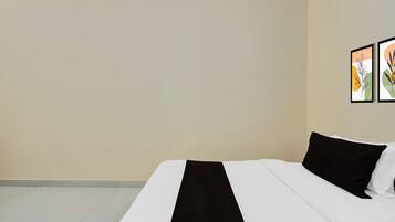 Una habitación de hotel con una cama, una pared blanca y dos cuadros enmarcados.