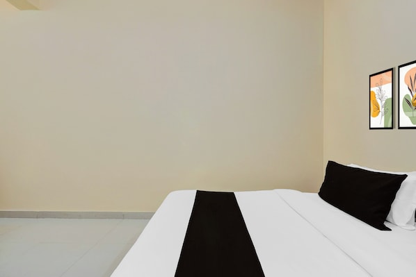A hotel room with a bed, a white wall, and two framed pictures. - Hotel O Kukas Bus Terminal (Amer)